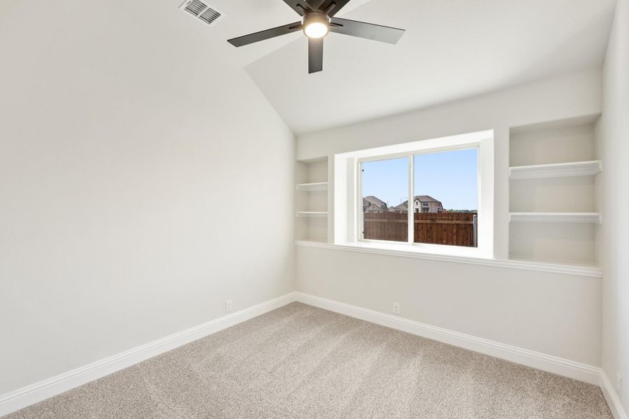 Empty bedroom with vaulted ceiling, ceiling fan, built-in shelves, and carpet flooring Empty bedroom with vaulted ceiling, ceiling fan, built-in shelves, and carpet flooring