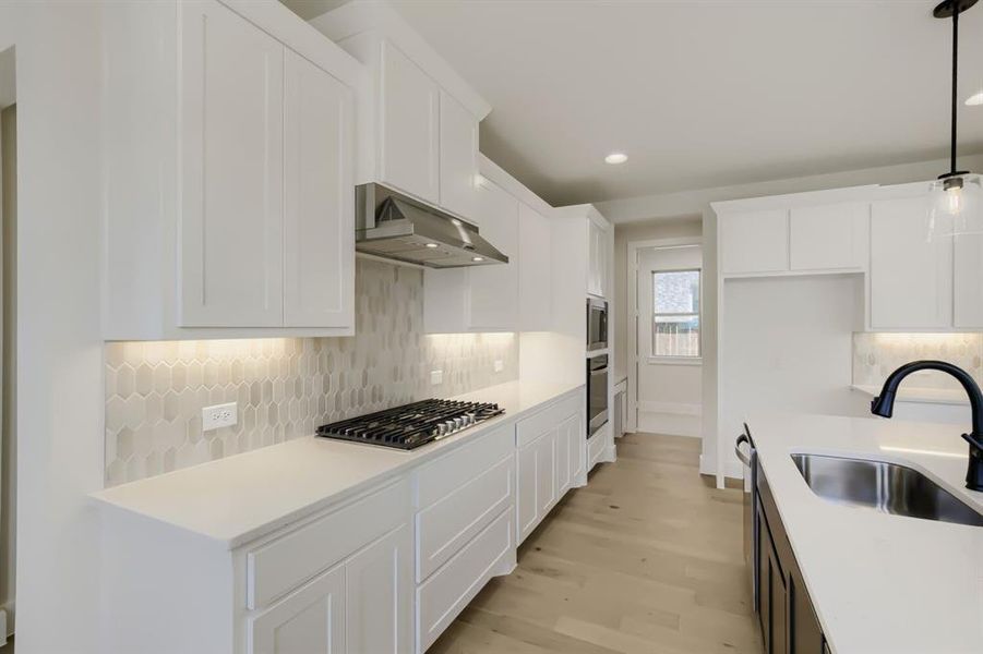 Modern kitchen featuring white shaker cabinetry and light-toned countertops