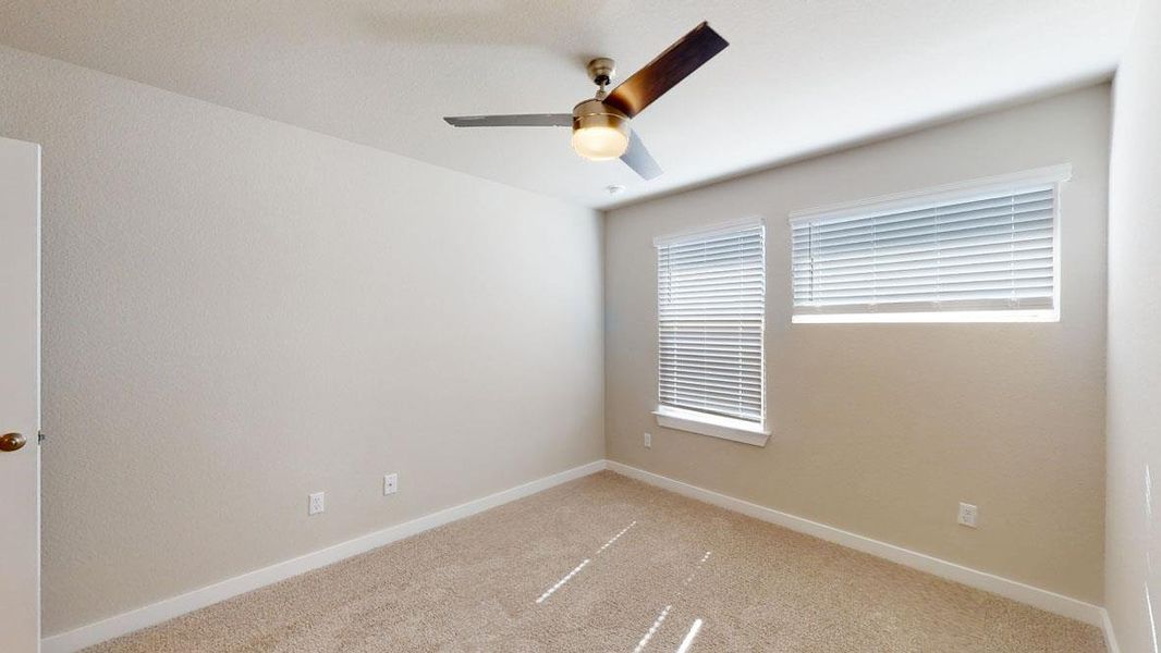 A well-lit bedroom provides comfort with soft carpeting and a contemporary ceiling fan. A well-lit bedroom provides comfort with soft carpeting and a contemporary ceiling fan.