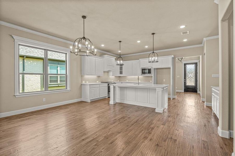 Kitchen featuring white cabinetry, stainless steel appliances, light hardwood / wood-style flooring, and a center island with sink