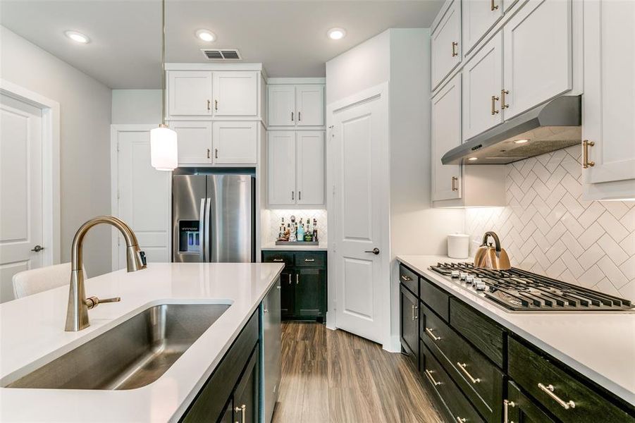 Kitchen featuring white cabinetry, sink, decorative light fixtures, appliances with stainless steel finishes, and hardwood / wood-style flooring