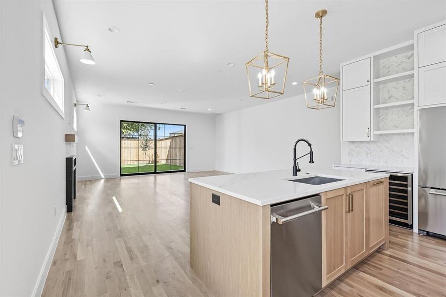 Kitchen featuring open shelves, open floor plan, hanging light fixtures, light brown cabinetry, and stainless steel appliances Kitchen featuring open shelves, open floor plan, hanging light fixtures, light brown cabinetry, and stainless steel appliances