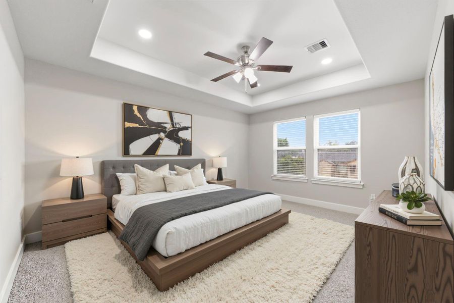 Beautiful primary suite showcases a tray ceiling, recessed lighting, and ceiling fan.*Virtually Staged