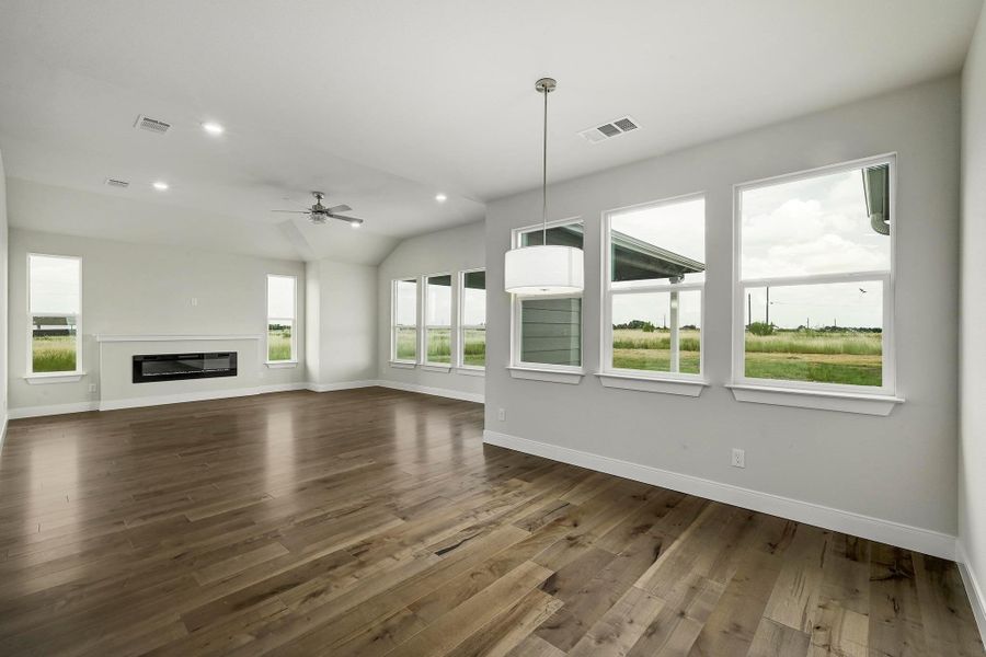 Unfurnished living room with dark wood-style flooring, ceiling fan, lofted ceiling, a glass covered fireplace, and recessed lighting Unfurnished living room with dark wood-style flooring, ceiling fan, lofted ceiling, a glass covered fireplace, and recessed lighting