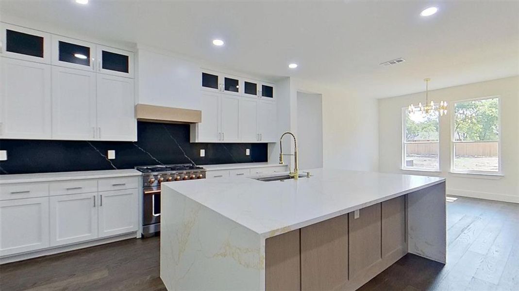 Kitchen with decorative backsplash, stainless steel range, light stone countertops, dark wood-type flooring, and recessed lighting