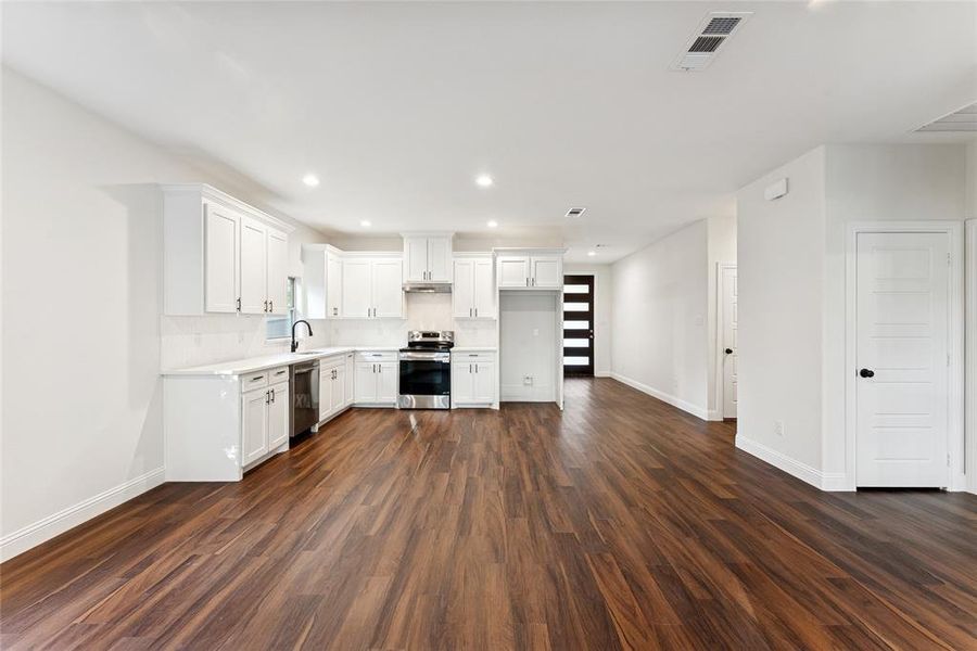 Kitchen with white cabinetry, appliances with stainless steel finishes, dark wood-style floors, and recessed lighting