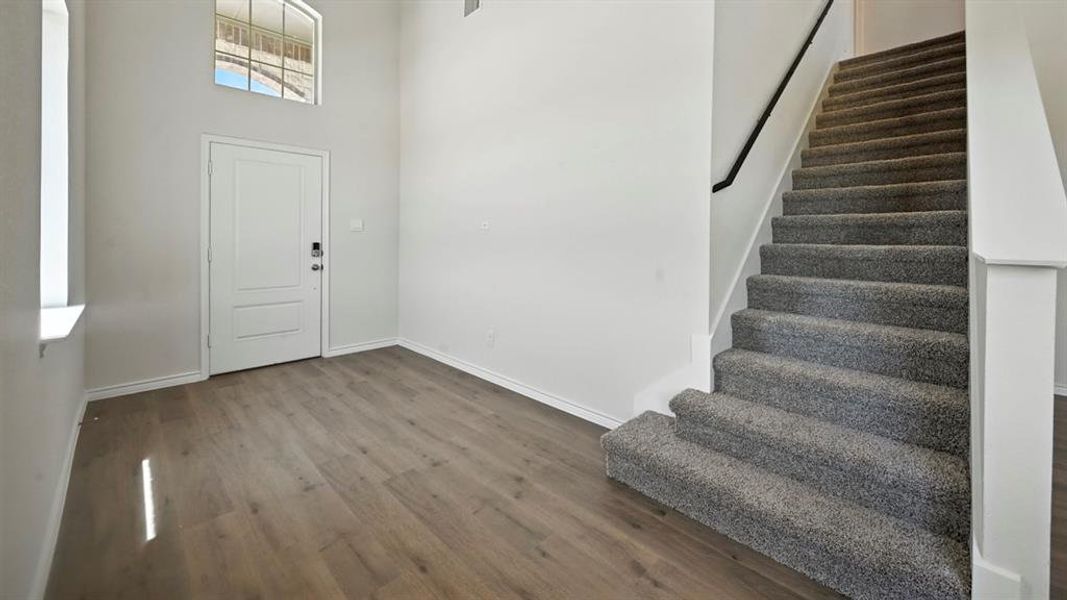 Entrance foyer featuring a towering ceiling, dark wood-style floors, and stairway