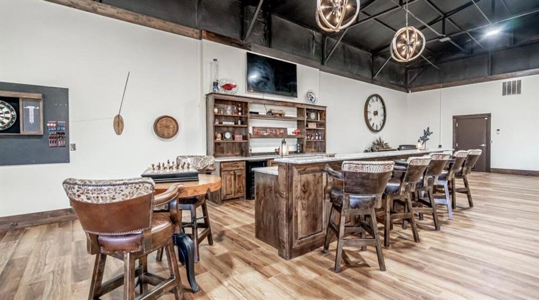 Indoor wet bar with open shelves, dark brown cabinetry, light wood-style flooring, and wine cooler Indoor wet bar with open shelves, dark brown cabinetry, light wood-style flooring, and wine cooler