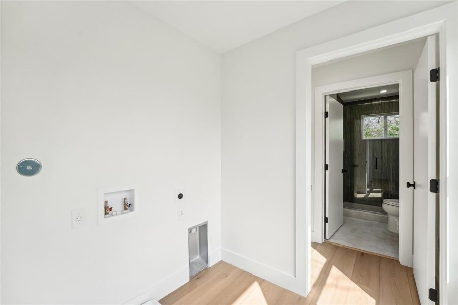 Clothes washing area with hookup for an electric dryer, light wood-style floors, hookup for a washing machine, and baseboards
