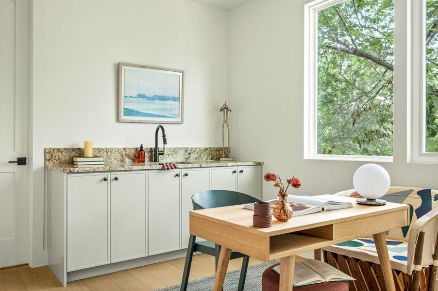Natural light floods this versatile home office, complete with a built-in wet bar and abundant storage.