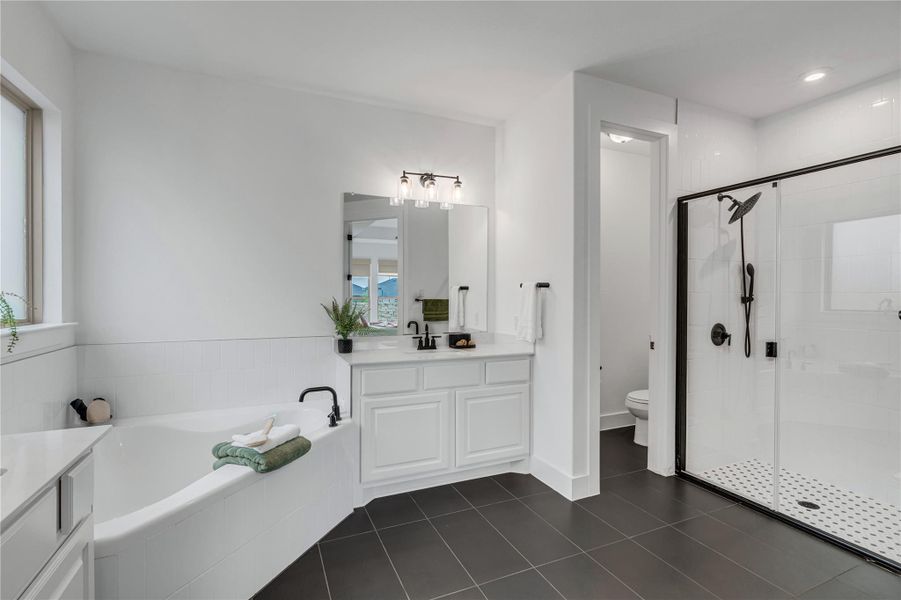 Luxurious primary bath featuring a deep soaking tub, separate shower, and elegant vanity with modern fixtures.