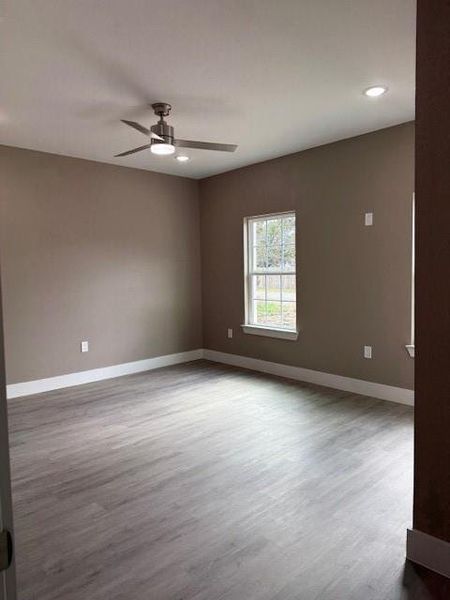 Spacious room featuring wood-finish flooring, a modern ceiling fan, and recessed lighting