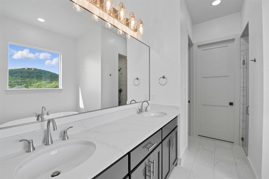 Full bath with a stall shower, recessed lighting, double vanity, light marble finish flooring, and a freestanding bath Full bath with a stall shower, recessed lighting, double vanity, light marble finish flooring, and a freestanding bath