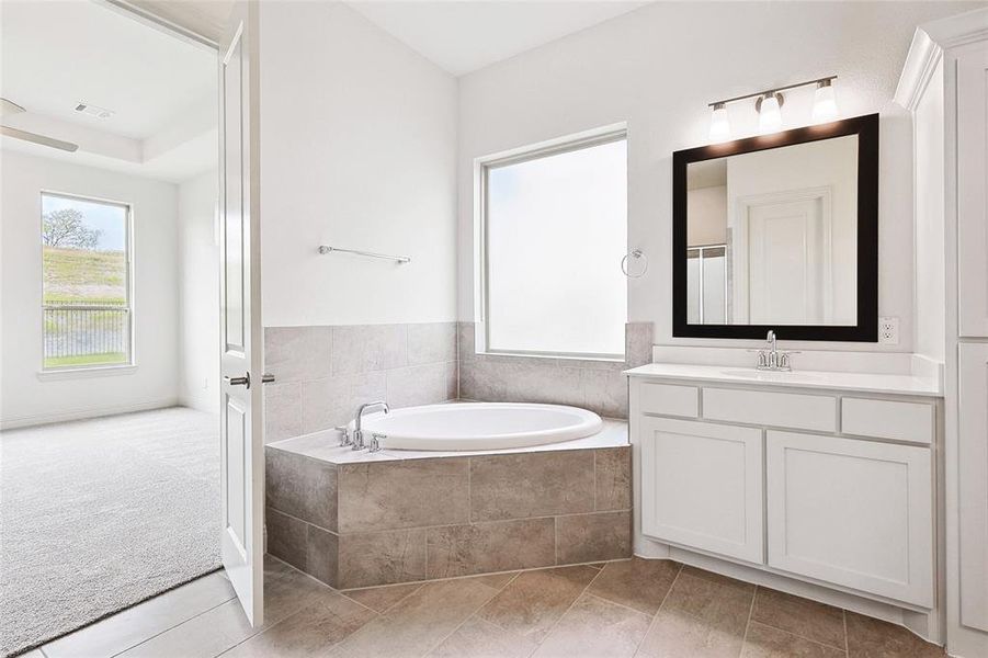 Bathroom featuring tile flooring, tiled bath, and vanity with extensive cabinet space