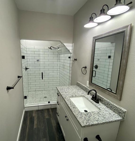 Bathroom with a shower with shower door, vanity, and hardwood / wood-style flooring