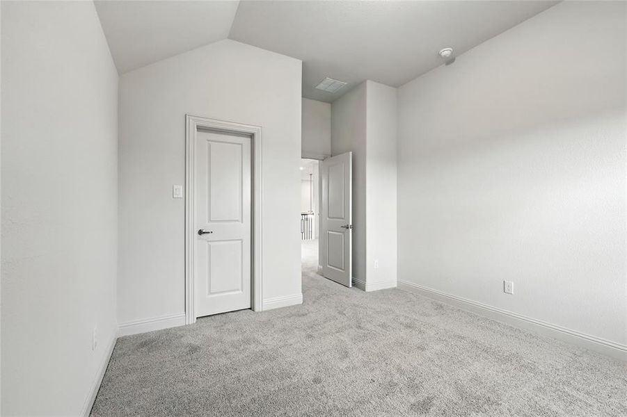 Unfurnished bedroom with light colored carpet and vaulted ceiling