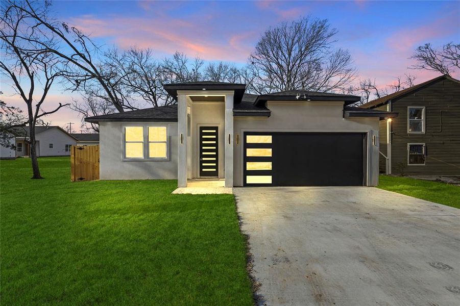 Prairie-style home with a garage and a lawn