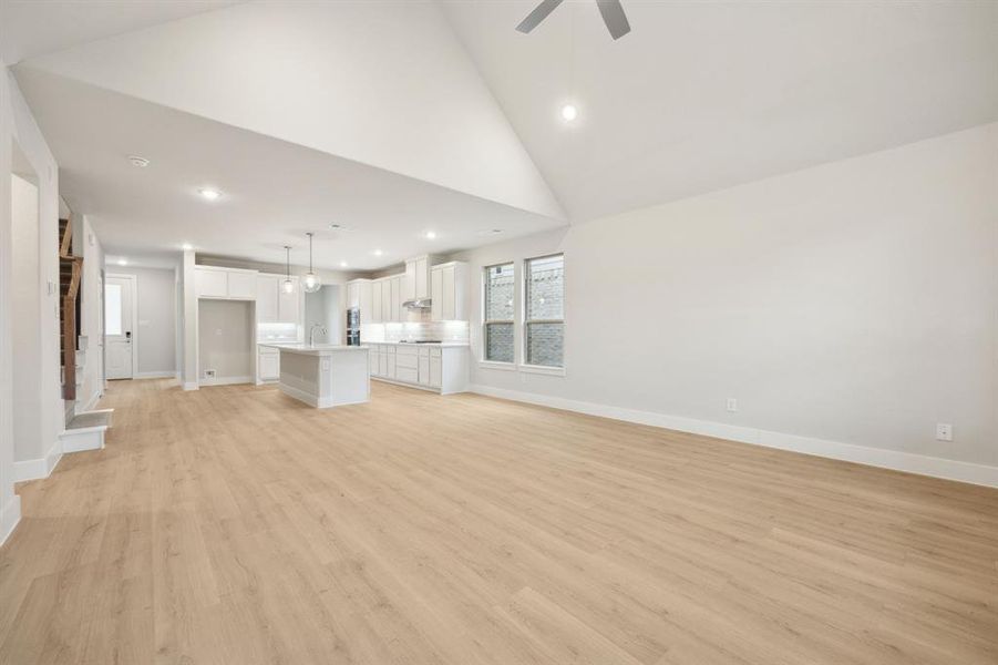 Unfurnished living room featuring ceiling fan, sink, high vaulted ceiling, and light hardwood / wood-style flooring