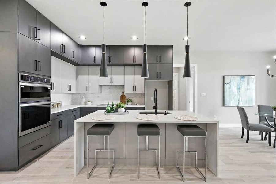 Kitchen featuring stainless steel double oven, light wood-type flooring, light countertops, tasteful backsplash, and a breakfast bar area Kitchen featuring stainless steel double oven, light wood-type flooring, light countertops, tasteful backsplash, and a breakfast bar area