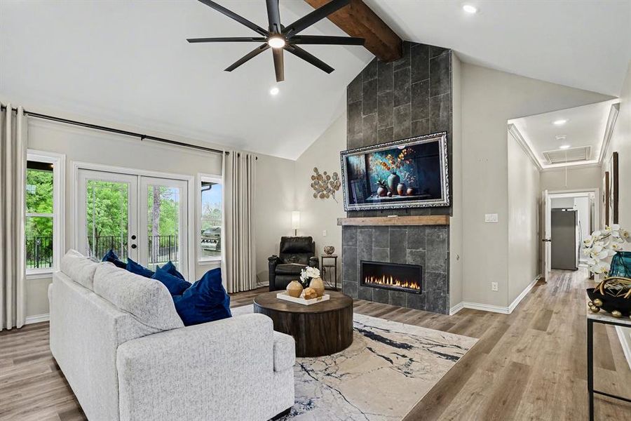 Living area featuring vaulted ceiling, a tiled fireplace, light wood finished floors, a ceiling fan, and recessed lighting