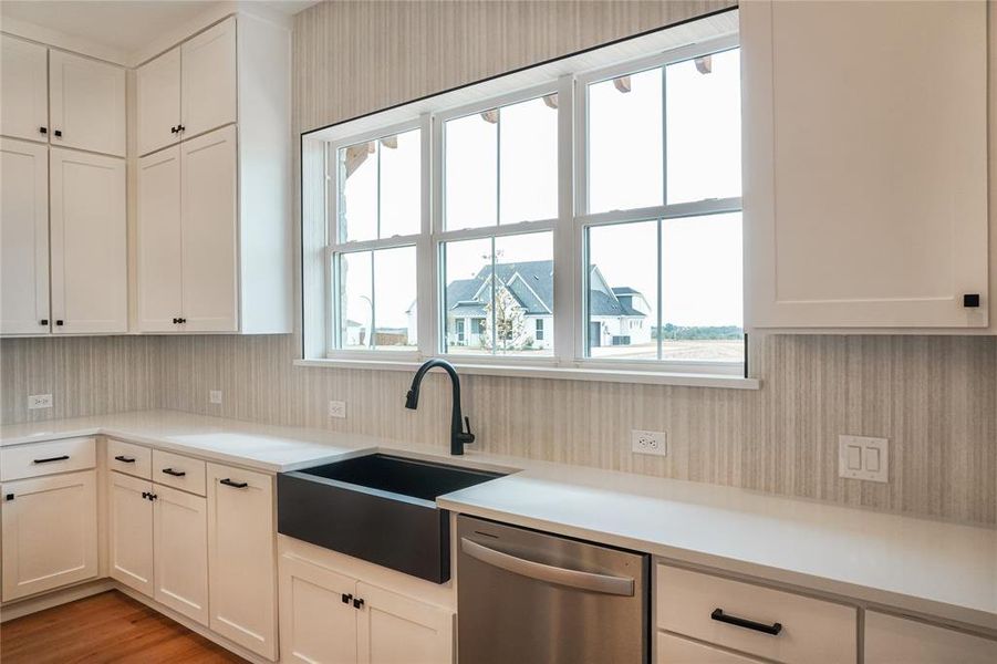 Kitchen featuring white cabinets, light wood-type flooring, stainless steel dishwasher, and sink