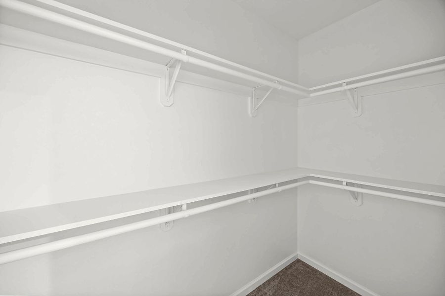 Spacious walk-in closet featuring double hanging rods and ample shelving for organized storage.