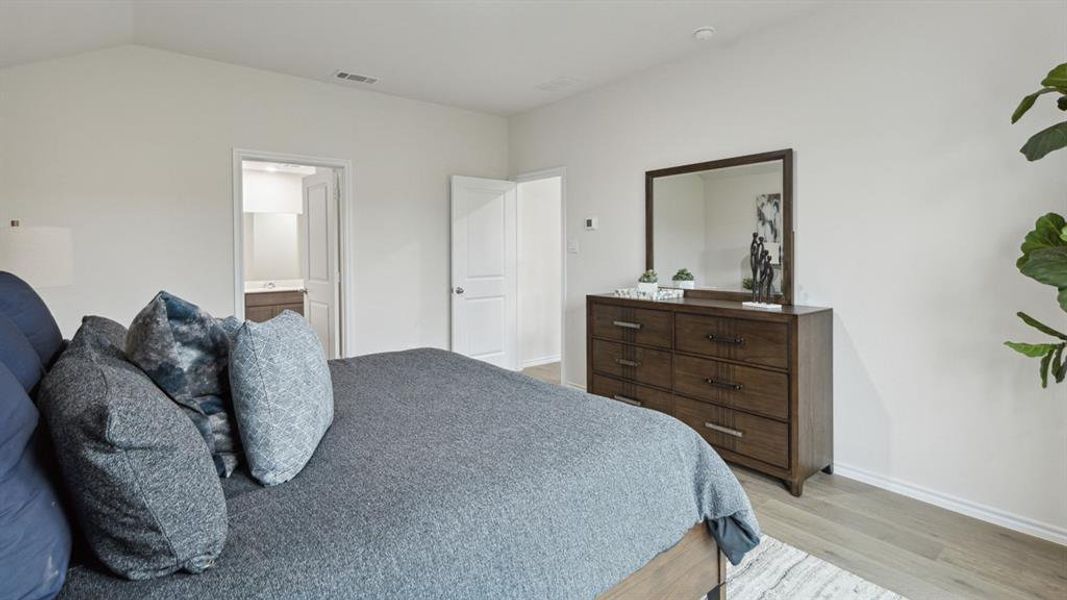 Bedroom featuring light wood finished floors and connected bathroom Bedroom featuring light wood finished floors and connected bathroom