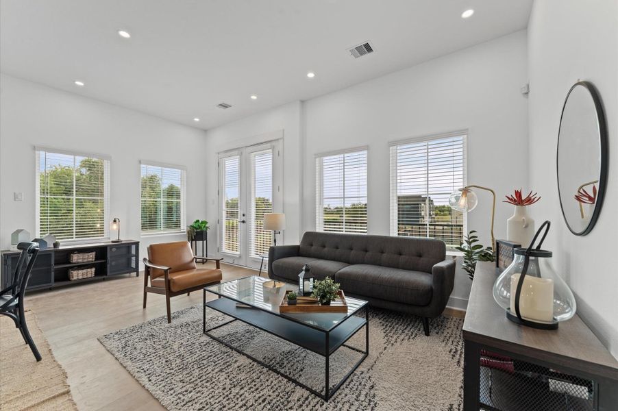 Second-story open-concept living, dining, and kitchen area bathed in natural light, featuring elegant French doors that lead to a private balcony with sweeping downtown views. The seamless layout offers effortless flow for entertaining, complemented by modern finishes and skyline vistas that elevate everyday living.