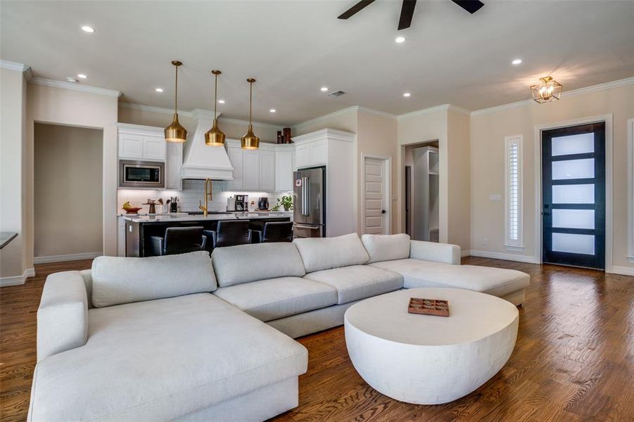 Living room with ceiling fan, dark hardwood / wood-style floors, and ornamental molding