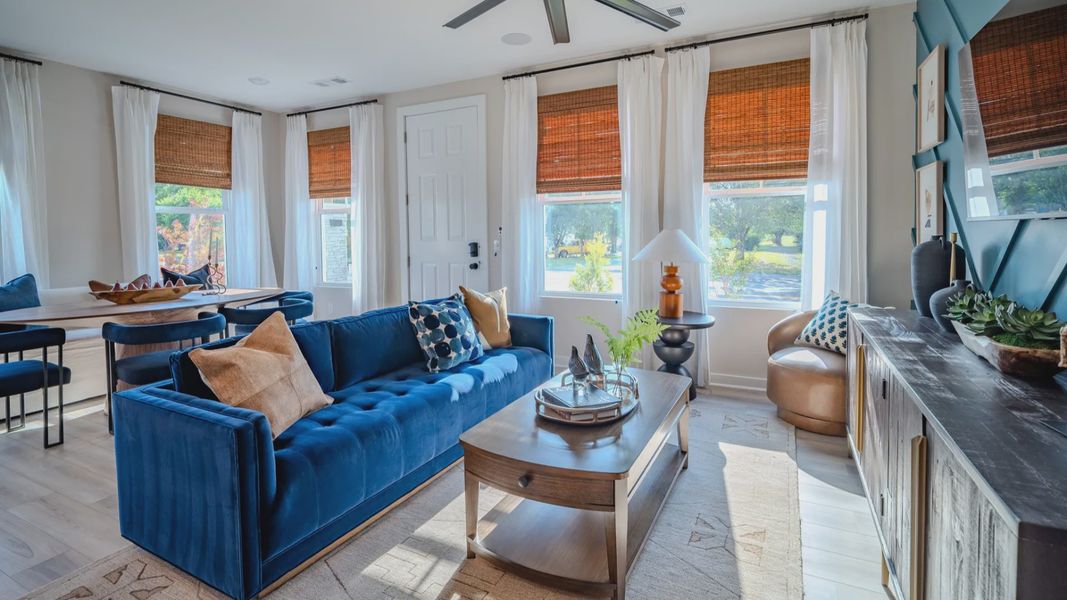 Living area with ceiling fan, accent wall, and access to dining area