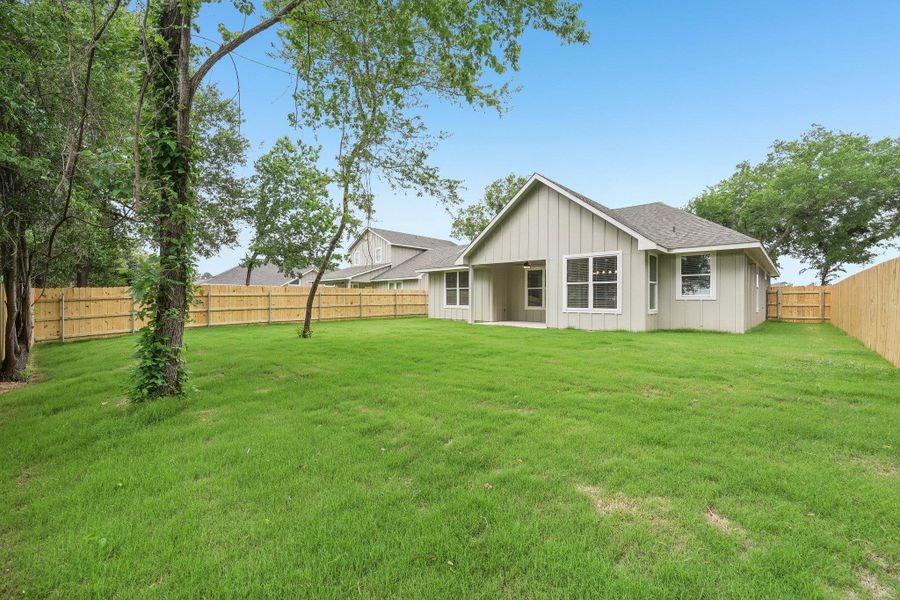 Back of house with board and batten siding, a lawn, a shingled roof, and a fenced backyard Back of house with board and batten siding, a lawn, a shingled roof, and a fenced backyard