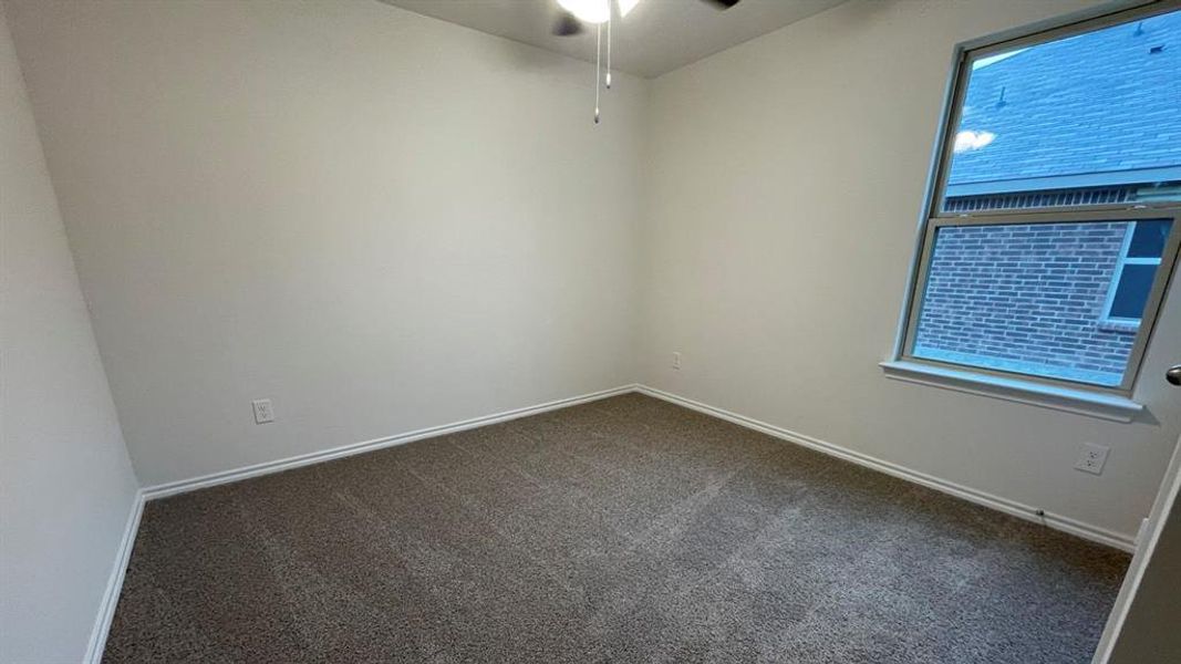 Carpeted room featuring a ceiling fan, white baseboards, and a double-pane window Carpeted room featuring a ceiling fan, white baseboards, and a double-pane window