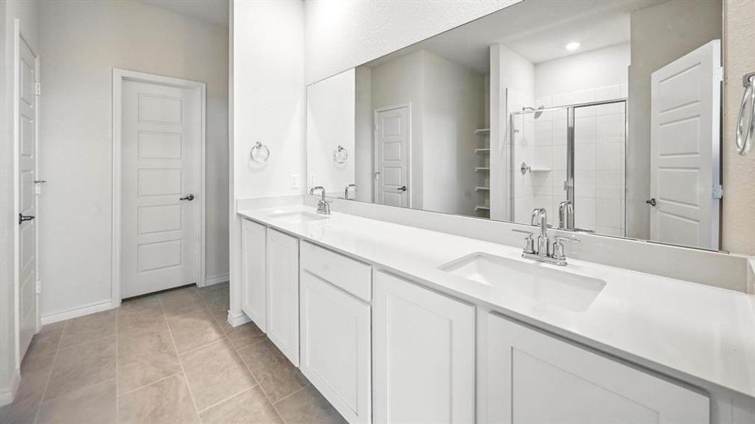 Double vanity featuring white cabinetry, integrated sinks, chrome fixtures, and a full-width mirror