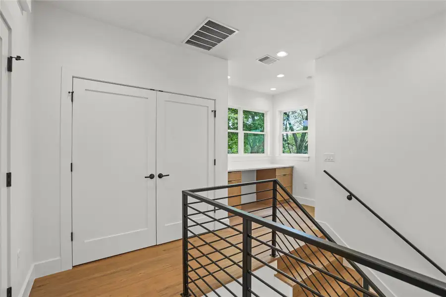 A well-lit landing features light wood flooring and modern railings, leading to an integrated desk space with abundant natural illumination.