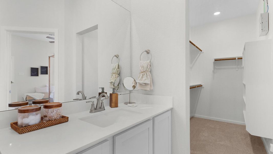A well-lit primary bathroom vanity with direct access to a spacious walk-in closet. A well-lit primary bathroom vanity with direct access to a spacious walk-in closet.