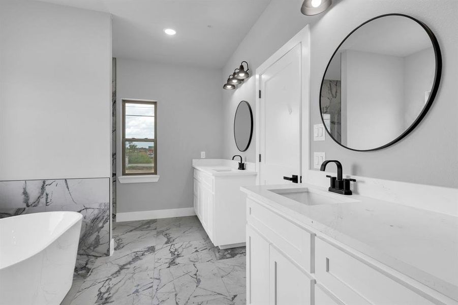 Full bath featuring two vanities, a soaking tub, light marble finish floors, and recessed lighting