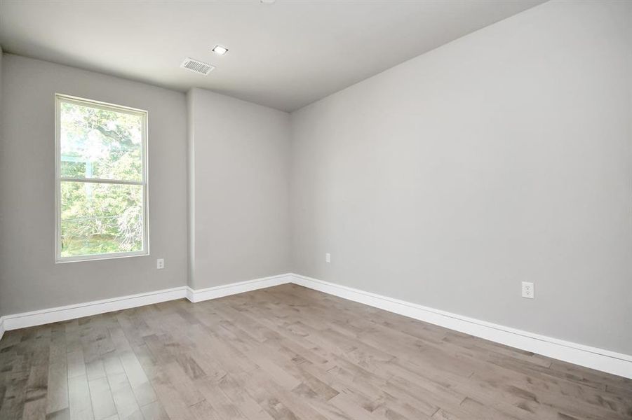 This is a modern, empty room featuring light grey walls, contemporary white doors, and pale wood flooring. It's well-lit with a clean, minimalist design, offering a blank canvas for personalization.