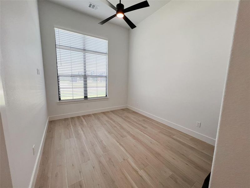 Empty room featuring light wood-type flooring and a ceiling fan