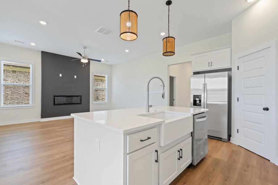 Kitchen island with a white farmhouse sink, stainless steel faucet, and white countertop Kitchen island with a white farmhouse sink, stainless steel faucet, and white countertop