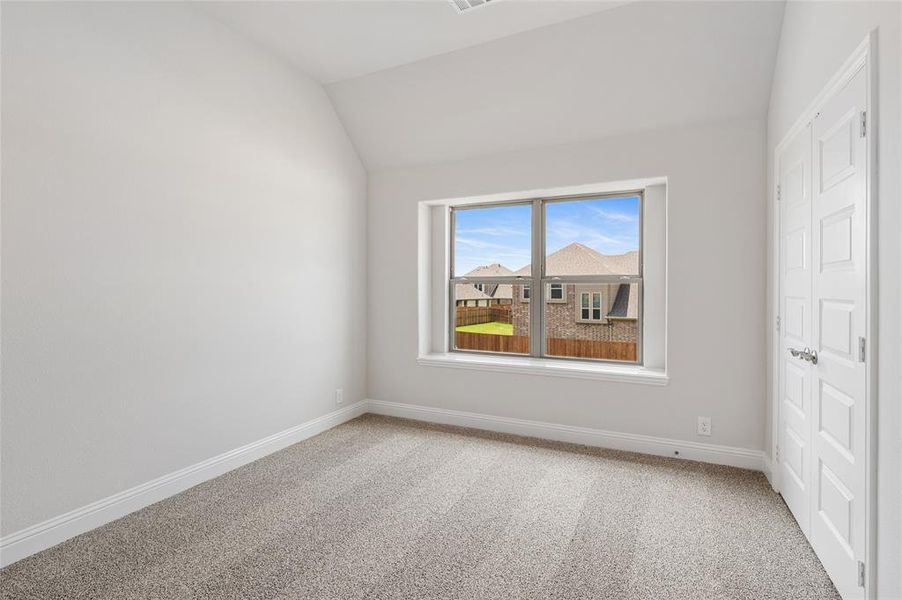 Unfurnished bedroom featuring light carpet and lofted ceiling