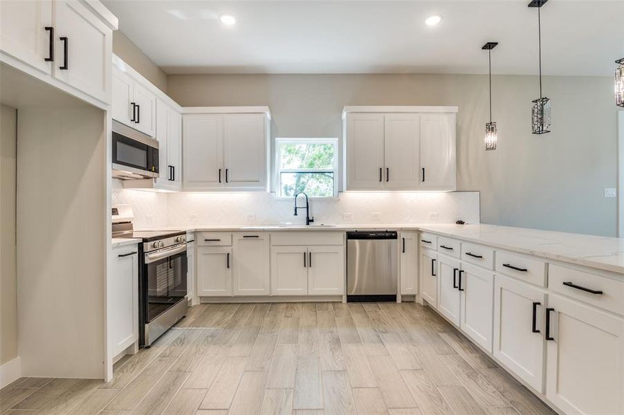 Kitchen with tasteful backsplash, white cabinets, light stone countertops, stainless steel appliances, and 9 inch sink Kitchen with tasteful backsplash, white cabinets, light stone countertops, stainless steel appliances, and 9 inch sink