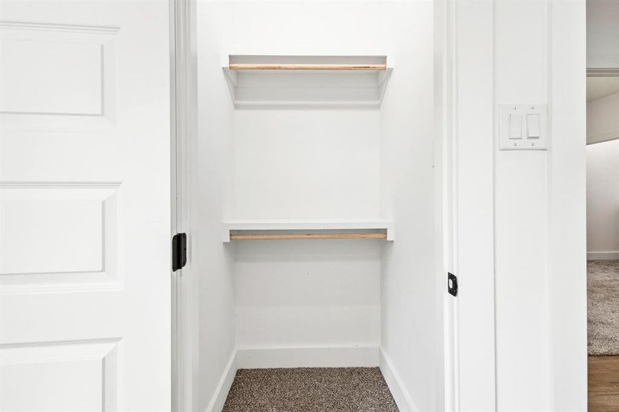 Recessed closet featuring two storage shelves, two hanging rods, and neutral-toned carpet flooring Recessed closet featuring two storage shelves, two hanging rods, and neutral-toned carpet flooring