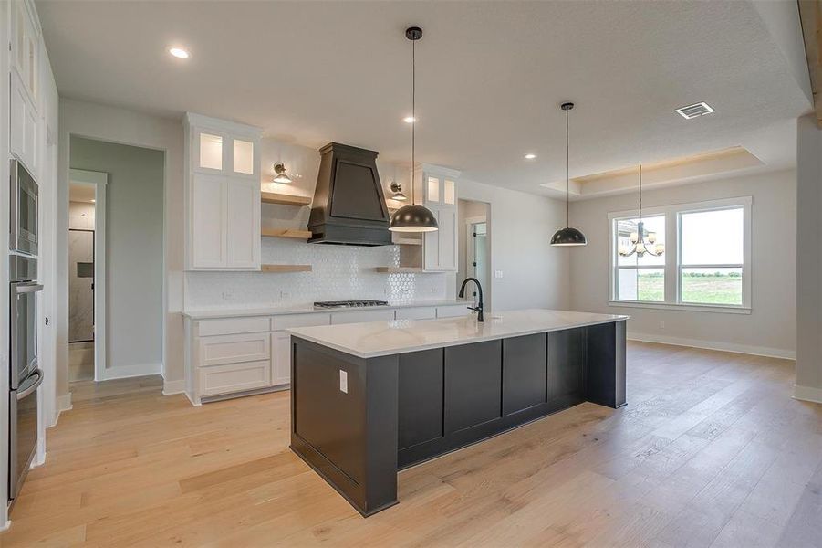 Kitchen featuring custom range hood, open shelves, white cabinets, visible vents, and stainless steel appliances Kitchen featuring custom range hood, open shelves, white cabinets, visible vents, and stainless steel appliances