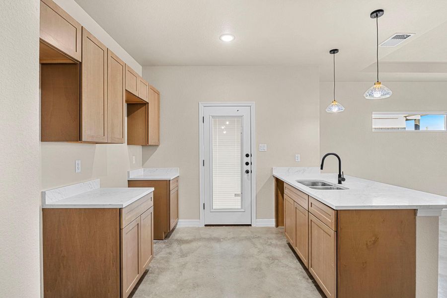 Kitchen featuring a peninsula, light stone countertops, decorative light fixtures, and wood finish cabinets