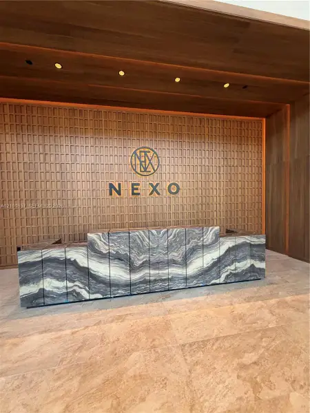 Reception area featuring stone-clad millwork, wood-paneled accent wall with integrated recessed lighting, and stone flooring