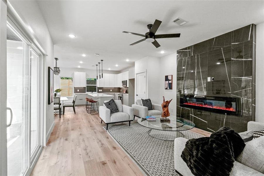 Living room with a tile fireplace, light hardwood / wood-style flooring, and ceiling fan