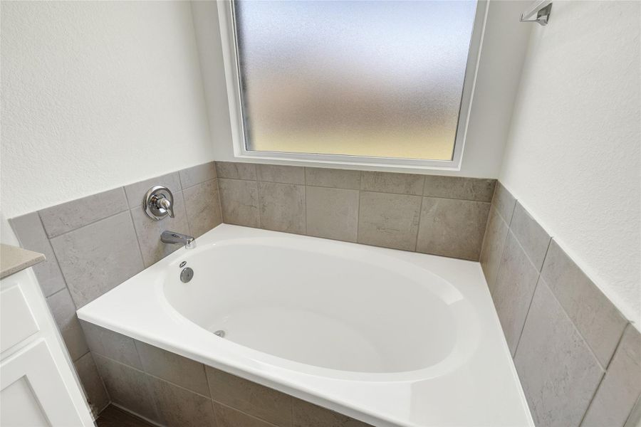 Indulge in relaxation with this elegant soaking tub, set against a backdrop of modern tiling.