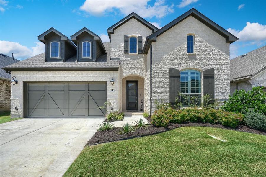 French country home with a garage and a front yard