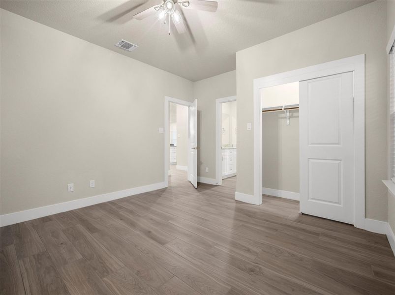 Unfurnished bedroom featuring wood finished floors, ceiling fan, a closet, and ensuite bathroom Unfurnished bedroom featuring wood finished floors, ceiling fan, a closet, and ensuite bathroom