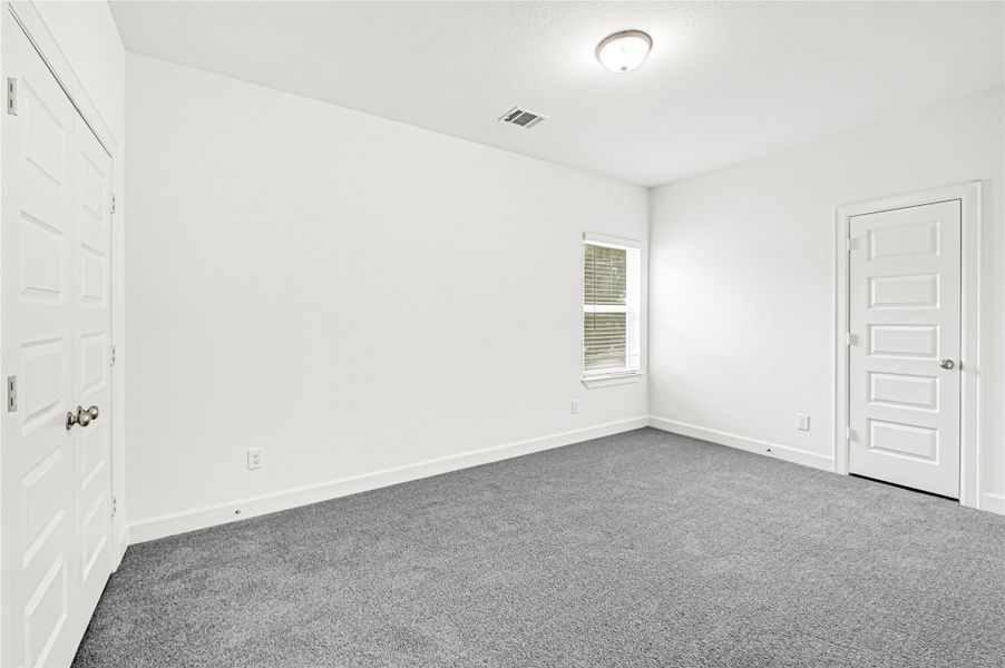 This photo shows a bright, empty room with neutral walls and carpet, featuring a window and two white doors. Ideal for a bedroom or office space. This photo shows a bright, empty room with neutral walls and carpet, featuring a window and two white doors. Ideal for a bedroom or office space.